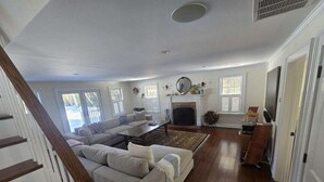 Ein geräumiges Wohnzimmer mit einer großen Couch, einem Kamin und einer Treppe.