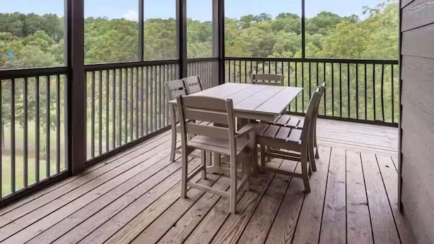 Een overdekt terras met een tafel, stoelen, grote ramen en een plafondventilator.