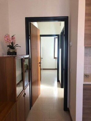 Un pasillo con un armario de madera a la izquierda y una puerta que da a otra habitación.