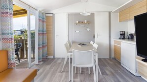 Una cocina moderna con una mesa de comedor, sillas blancas y un televisor.