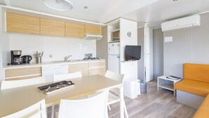 Cocina compacta con muebles blancos, una mesa de comedor y un pequeño rincón de estar con un sofá naranja.