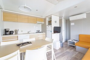 Une cuisine compacte avec des meubles blancs, une table à manger et un petit coin salon agrémenté d’un canapé orange.