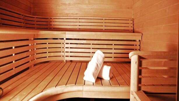 Un sauna en bois avec des bancs et une serviette sur le sol.