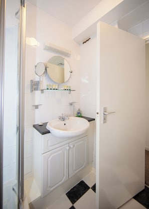 Un baño con lavamanos blanco, un espejo y ducha.