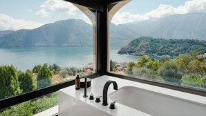 Un baño con un amplio ventanal que ofrece vistas a un lago y montañas.
