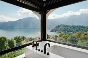 A bathroom with a large window offering a view of a lake and mountains. - Villa Magnifica by My Villa Collection (Lenno)