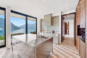 Eine moderne Küche mit einer großen Kochinsel, Meerblick und einer gemusterten Spritzschutzwand.