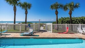Un espace piscine avec des chaises longues, un panneau indiquant une profondeur de 4 pieds, et une vue sur l’océan.
