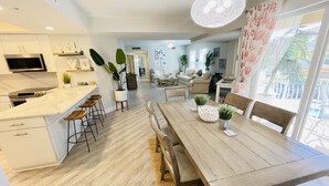 Une cuisine moderne avec des meubles blancs, une table à manger en bois et des tabourets de bar.