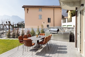 An outdoor patio with a table and chairs, a grill, and a view of a building with a tiled roof. - Villa la Petite by My Villa Collection (Lenno)