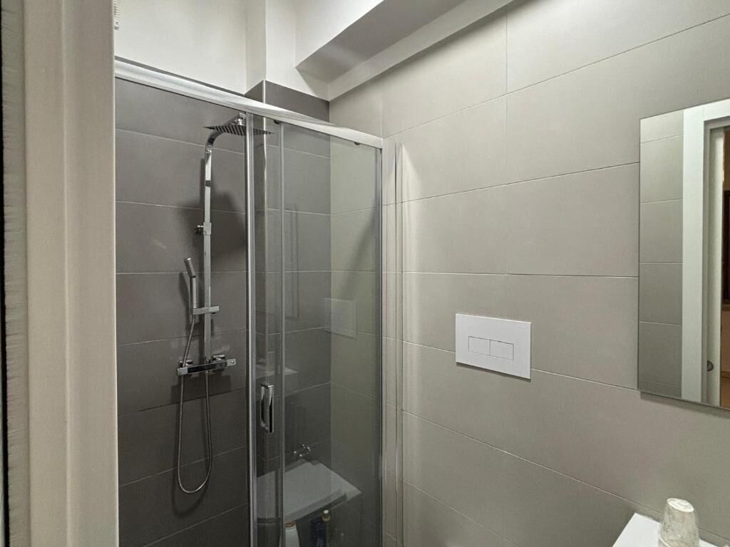 Un baño moderno con ducha de vidrio, lavamanos y espejo.