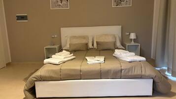 A neatly made bed with a beige comforter and pillows, two bedside tables with lamps, and two framed floral artworks on the wall.