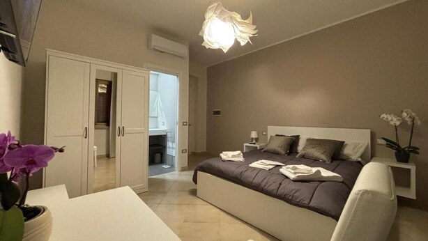 Une chambre à coucher avec un lit, une table de chevet et un luminaire au plafond.