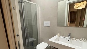 Une salle de bain moderne avec une douche à parois de verre, des toilettes blanches et un meuble-lavabo avec un miroir.