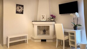Un salon moderne avec une cheminée, un téléviseur à écran plat fixé au mur et un canapé blanc.