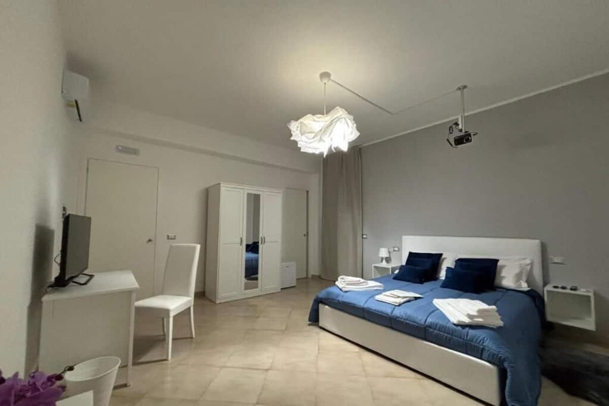 Un dormitorio con cama, una silla, un escritorio y un televisor.
