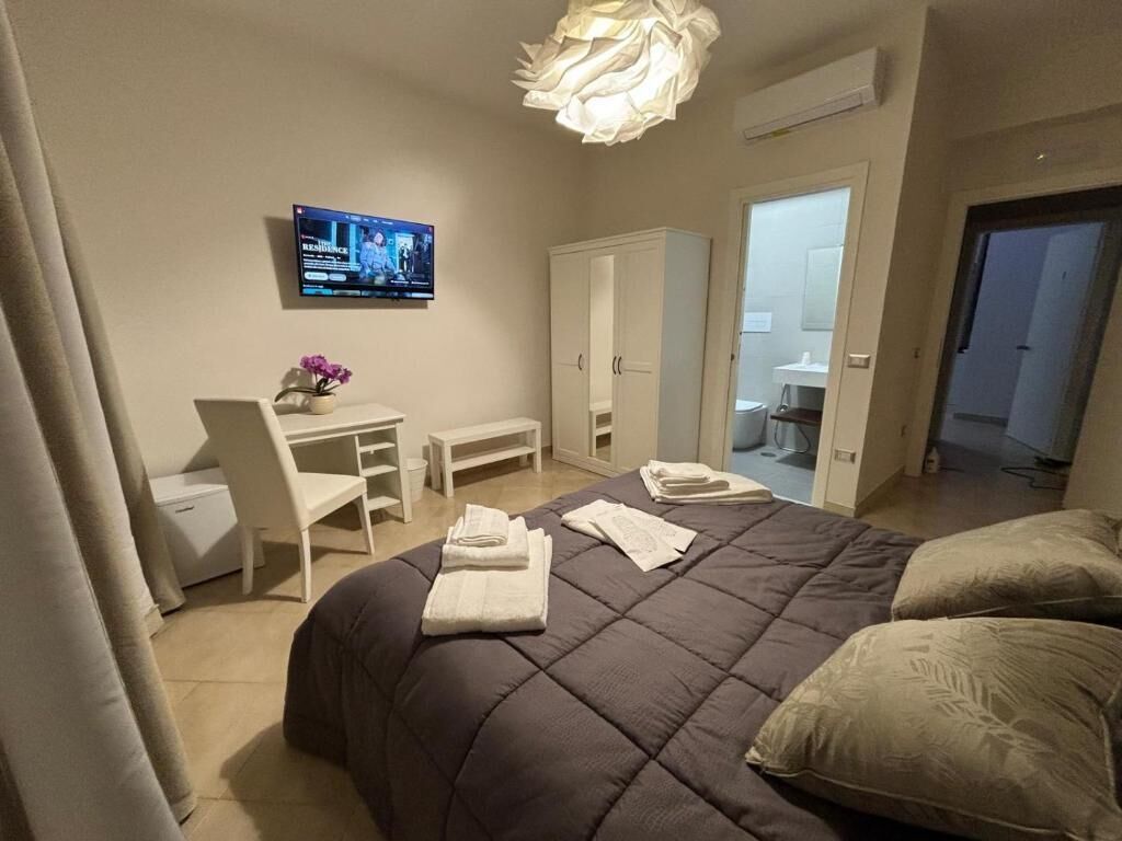 Een slaapkamer met een bed, een bureau, een stoel en een televisie aan de muur.