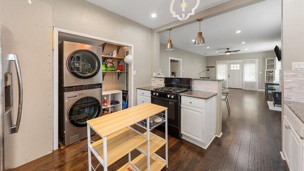 Una cocina con lavadora y secadora integradas, una estufa y un comedor con mesa y sillas.