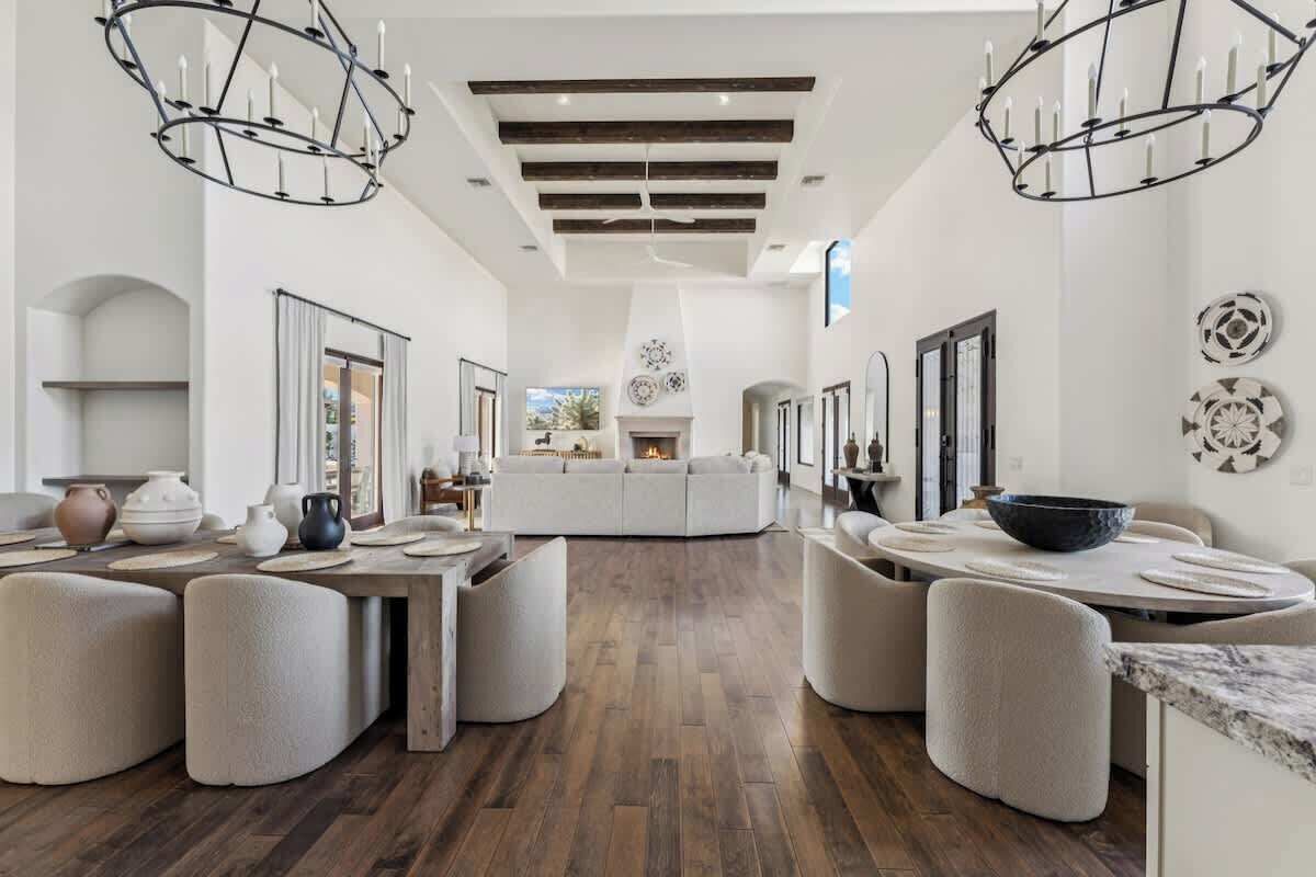 Un amplio salón con chimenea central, piso de madera y muebles modernos.