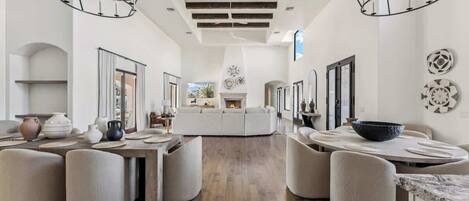 Un amplio salón con chimenea central, piso de madera y muebles modernos.