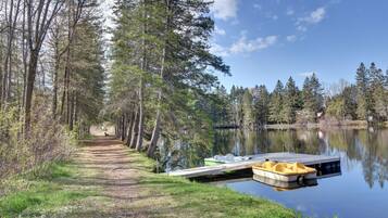 A tranquil lakeside path with a dock and a yellow boat.