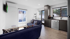 Ein modernes Wohnzimmer mit einer Couch, einem Glastisch und Blick ins Freie.