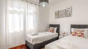 Une chambre avec deux lits, une table de chevet, une lampe et des œuvres d’art accrochées au mur.