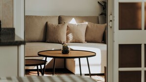 Un salon moderne avec un canapé beige, deux petites tables basses rondes et une petite plante en pot.