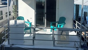 Een boot met een overdekt dek, waarop 'BONE FISH' staat, met twee stoelen en een deur naar een binnenruimte.