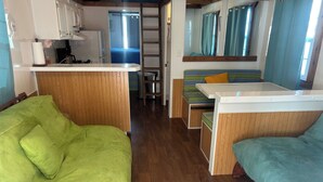 Een compacte leefruimte met een kitchenette, een eethoek en een slaapgedeelte met een stapelbed.