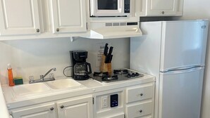 Een keuken met witte kasten, een magnetron, een fornuis en een koelkast.