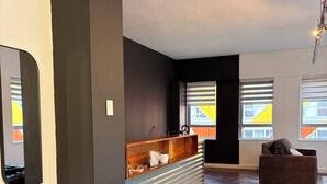 Amplia zona de estar con una pared oscura, un mostrador de recepción de madera y un espejo grande.