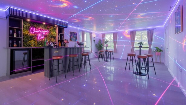Zona de bar con letreros de neón, varios taburetes y un diseño interior moderno.