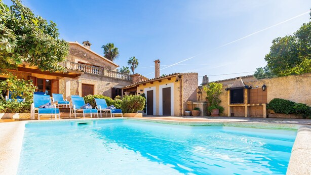 Piscina com espreguiçadeiras, um edifício com varanda e uma chaminé.