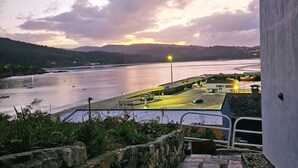 Gradians de pedra que porten a un balcó amb vista al passeig marítim i un cel al capvespre.
