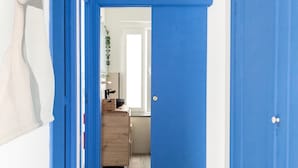 Un passadís amb portes blaves que donen a una habitació amb terra de fusta i paret blanca.