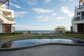Un bâtiment moderne doté d’une piscine, offrant une vue sur la mer et comprenant un espace aménagé avec des bancs.
