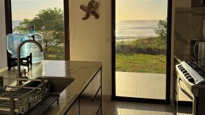 A modern kitchen with a large island, a view of the ocean, and a starfish decoration on the wall. - Hacienda Iguana Beachfront 3BR · Surf & Sunset (Tola)