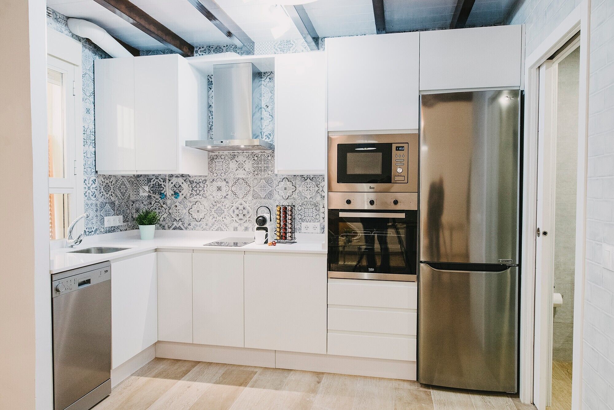 A modern kitchen with white cabinets, a stainless steel refrigerator, a built-in oven, and a microwave.