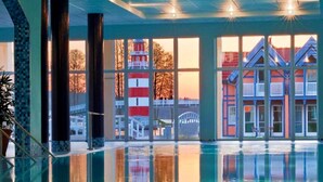 Ein Schwimmbad mit Blick auf ein rot-weißes Gebäude und eine Brücke im Hintergrund.