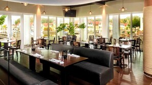 Ein Restaurant mit großen Fenstern, Tischen und Stühlen für Speisen.