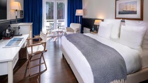 Ein Hotelzimmer mit Bett, Schreibtisch, Stuhl, kleinem Tisch und einem Balkon.