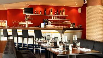 Un restaurante con barra, mesas y sillas.