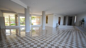 A spacious lobby with a checkered floor, large columns, and a view of the outdoors. - Studio With Shared Pool (Lignano Sabbiadoro)