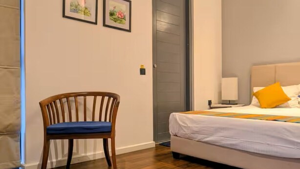 A bedroom with a bed, a chair, and two framed pictures on the wall. - Private bedroom with ensuite bathroom in Colombo 5 (Colombo)