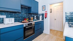 Une cuisine moderne avec des meubles bleus, un plan de travail blanc, un grille-pain, une machine à café et un évier.