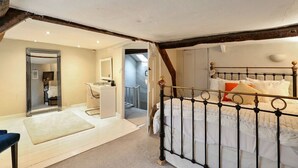 Une chambre à coucher comprenant un lit, un miroir, une commode et une porte donnant sur une autre pièce.