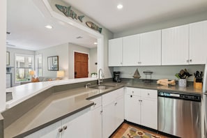 A modern kitchen with white cabinets, stainless steel appliances, and a built-in dishwasher. - Harbour Oaks 419 ground floor, sleeps 6 (St Simons Island)