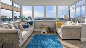 A spacious living room with large windows, a blue rug, and two sofas. - Tan-Y-Foel (Dyffryn Ardudwy)
