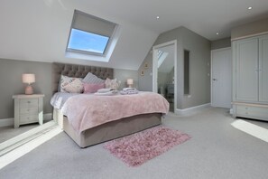 Ein Schlafzimmer mit Bett, Oberlicht, Kleiderschrank und Spiegel.